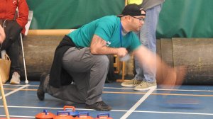 image of a man bending down as he throws a ball for indoor boccia